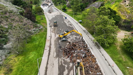 aerial view away from a excavator clearing a road, after fires in palisades, la