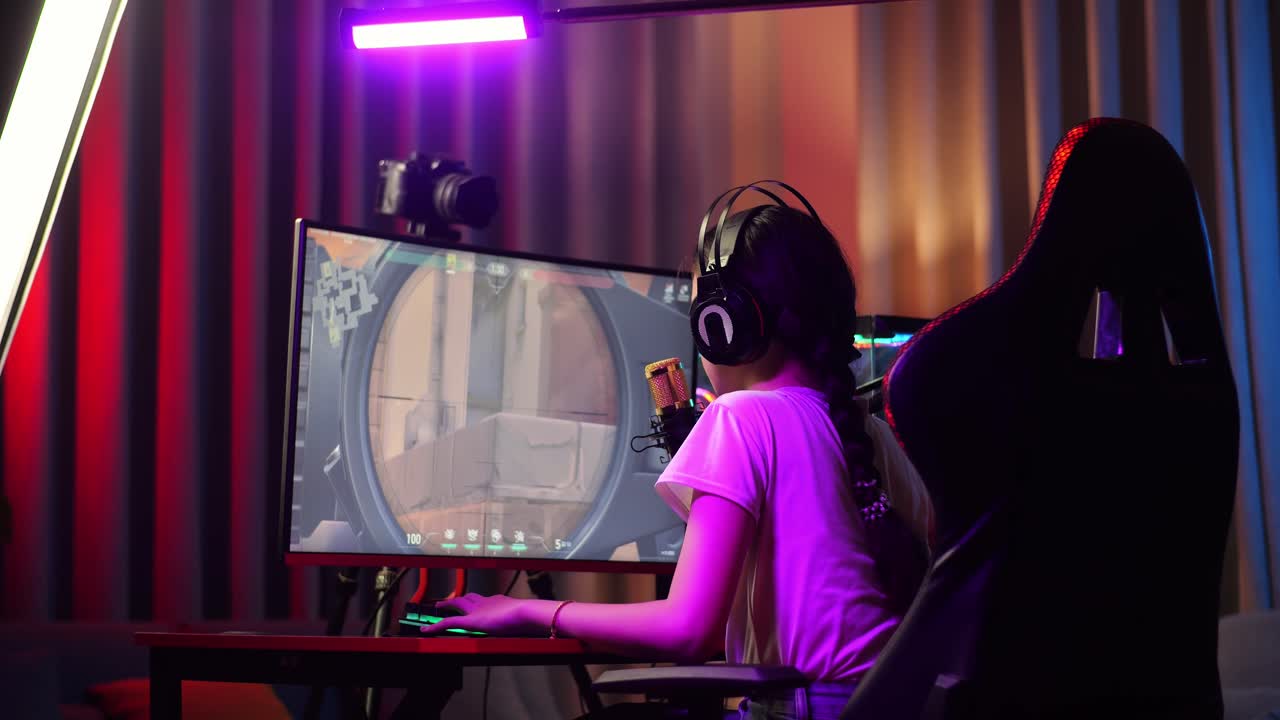 vista trasera de una chica asiática jugando a un juego a través de la red en una computadora personal. bostezando y durmiendo, videojuego de transmisión en vivo, escritorio iluminado por luz de tira led rgb