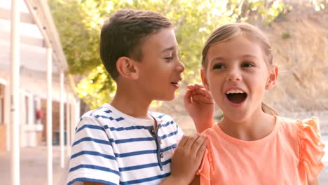 schoolboy whispering into his friend ear