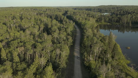 White-truck-driving-along-rural-road-on-Boreal-Forest,-Saskatchewan,-Canada