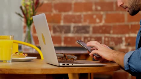 hombre guapo usando teléfono móvil y computadora portátil en la mesa 4k