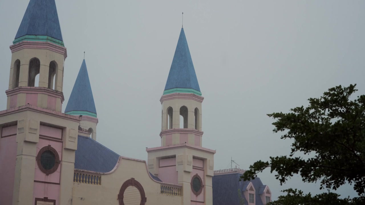 Árvores balançando e chuva visível enquadram uma arquitetura de torre distinta durante tempo sombrio, fornecendo imagens atmosféricas para temas de chuva, tempestades, clima e turismo.