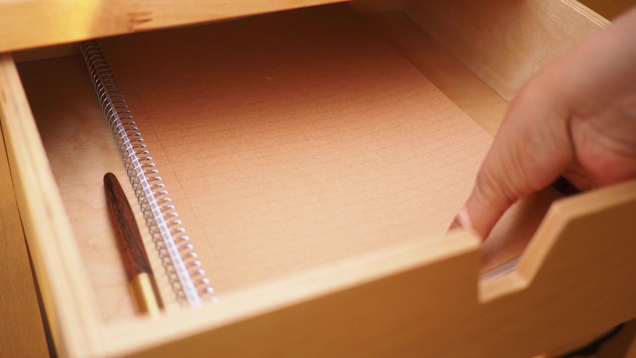 An empty drawer contains a notebook along with a pen placed inside