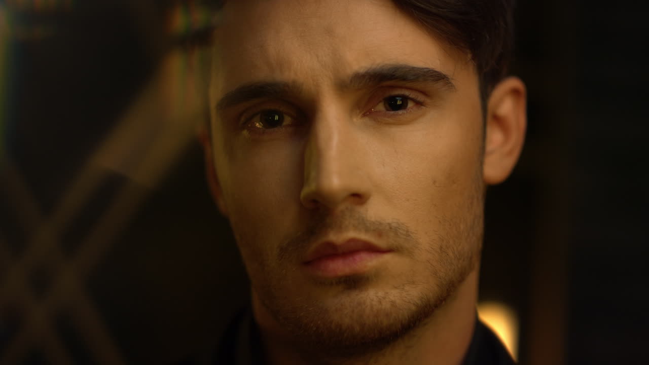 hombre enfocado girando la cabeza en el interior. persona masculina tranquila buscando cámara interior oscuro.