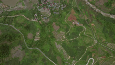 Vista-Aérea-De-Exuberantes-Arrozales-En-Terrazas-Y-Un-Pueblo-En-Sapa,-Vietnam