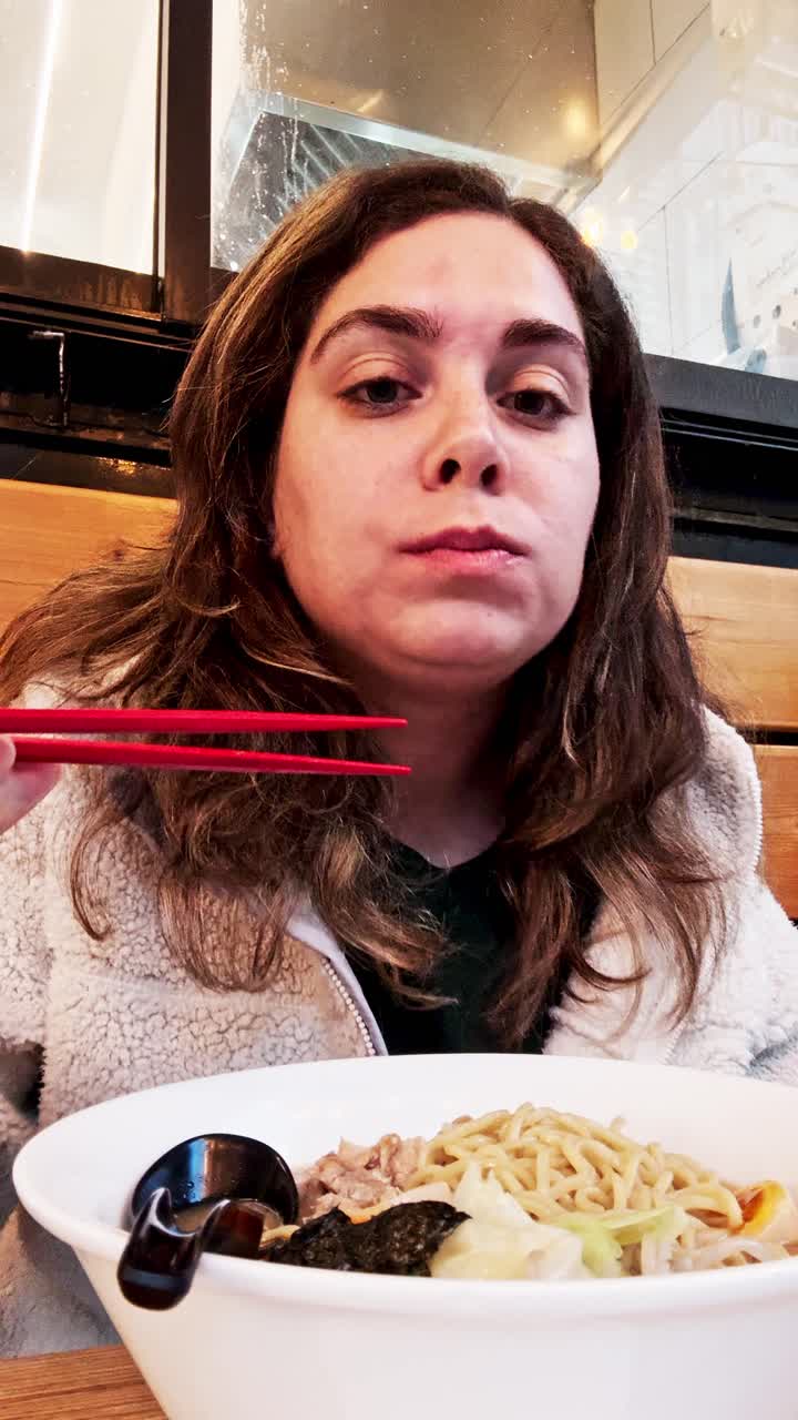 Joven comiendo fideos ramen japoneses con palillos