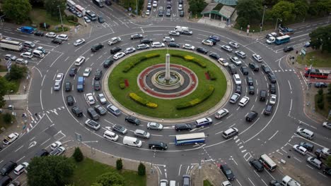 aerial view of busy traffic at a roundabout, showcasing complex vehicle movement and road design with cars and landscaping elements in urban setting