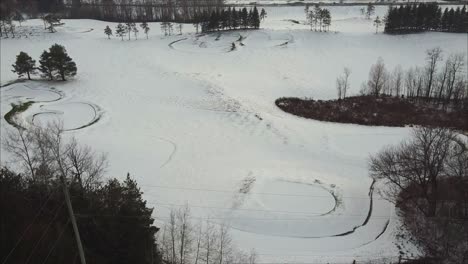 toma aérea ascendente de un campo de golf cubierto de nieve fresca durante el invierno