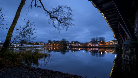 Día-A-Noche-Timelapse-Del-Santo-Grial-De-Carrick-En-El-Puente-De-La-Ciudad-De-Shannon-En-El-Condado-De-Leitrim-Y-Roscommon-Con-Tráfico,-Personas-Y-Nubes-Nocturnas-En-Movimiento-En-El-Río-Shannon-En-Irlanda