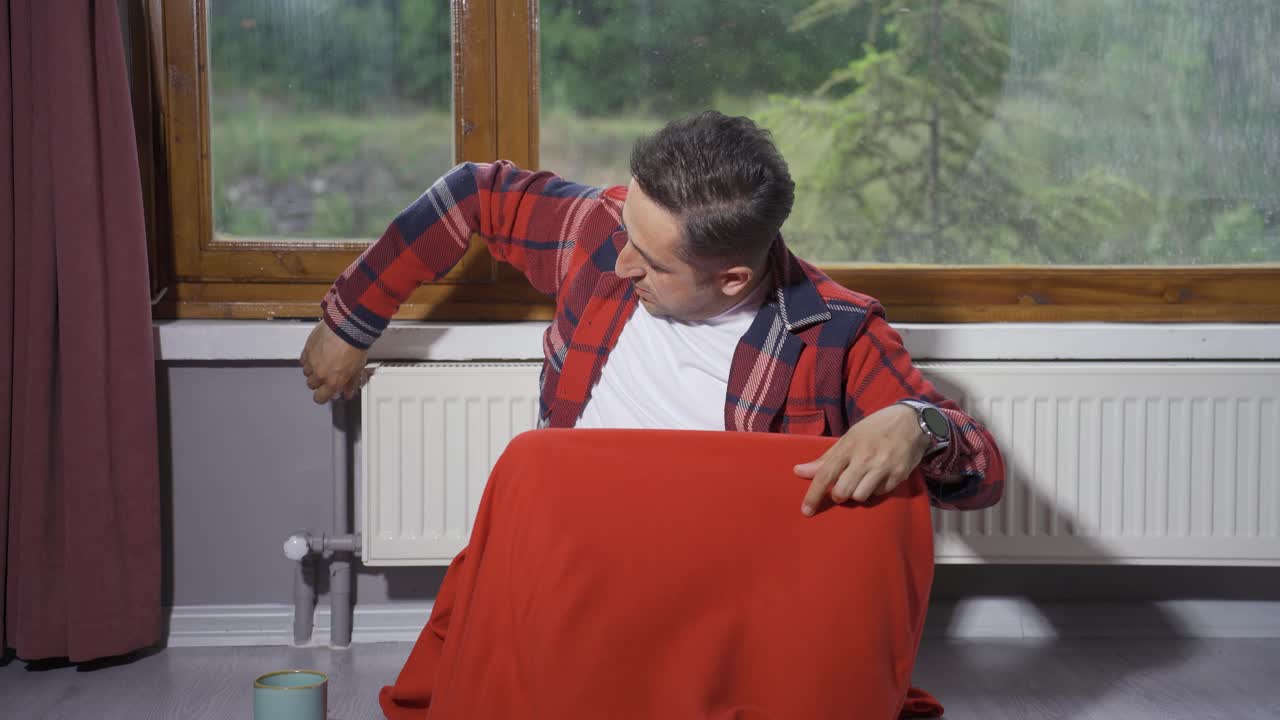 남자는 난방기의 온도를 낮추고 추워집니다.