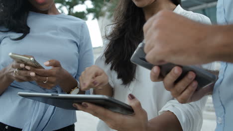 três pessoas do lado de fora com dispositivos eletrônicos, gesticulando ativamente