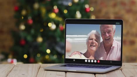 Pareja-De-Ancianos-Caucásicos-Saludando-En-Videollamada-En-Una-Computadora-Portátil,-Con-árbol-De-Navidad