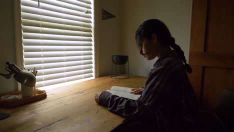 puerto rican student female sitting reading educational book by bedroom desk window