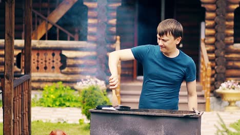hombre en cámara lenta cocina pilaf en un caldero en carbón en una parrilla agitar la carne