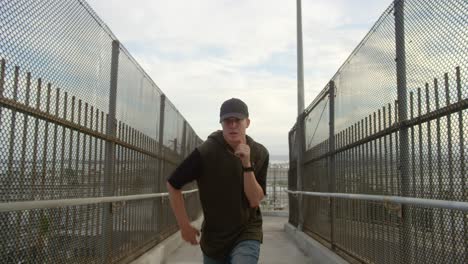 man freestyle hip hop dancing across freeway overpass in city
