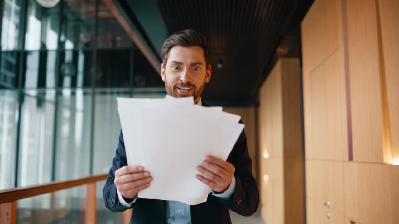 Executive examining documents excitement walking office hallway. Emotional man