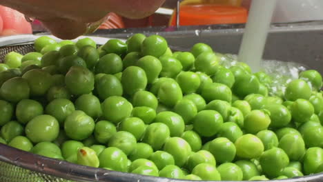 imágenes de mujer lavando y enjuagando guisantes verdes con colador de inox en un fregadero a cámara lenta