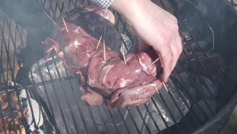 Placing-a-topside-of-venison-wrapped-in-bacon-on-a-grid-to-smoke