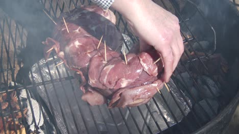 colocando una parte superior de venado envuelto en tocino en una rejilla para fumar