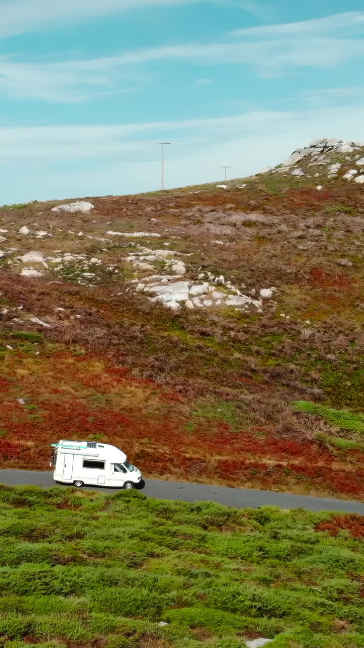 Camper bianco in viaggio su una strada panoramica attraverso un paesaggio collinare