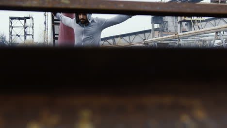 Deportista-Caucásico-Con-Una-Capucha-Gris-Haciendo-Ejercicios-Y-Calentándose-Antes-Del-Entrenamiento-De-Boxeo-Al-Aire-Libre-En-Una-Fábrica-Abandonada-En-Una-Mañana-Nublada