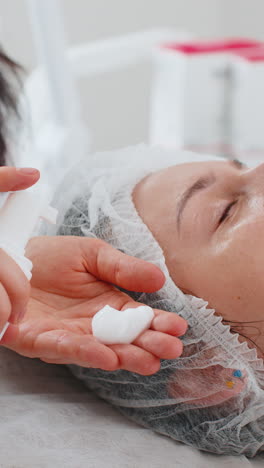 cosmetologist preparing to apply squeezes wash foam out from bottle moisturizing peeling woman face