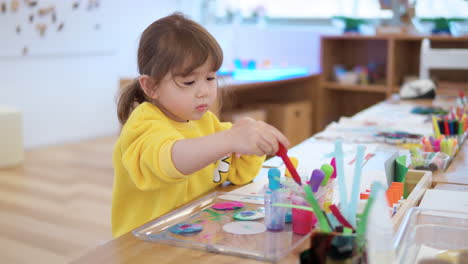 preschooler girl mix colors in containers with dropper during drip drawing watercolor lesson