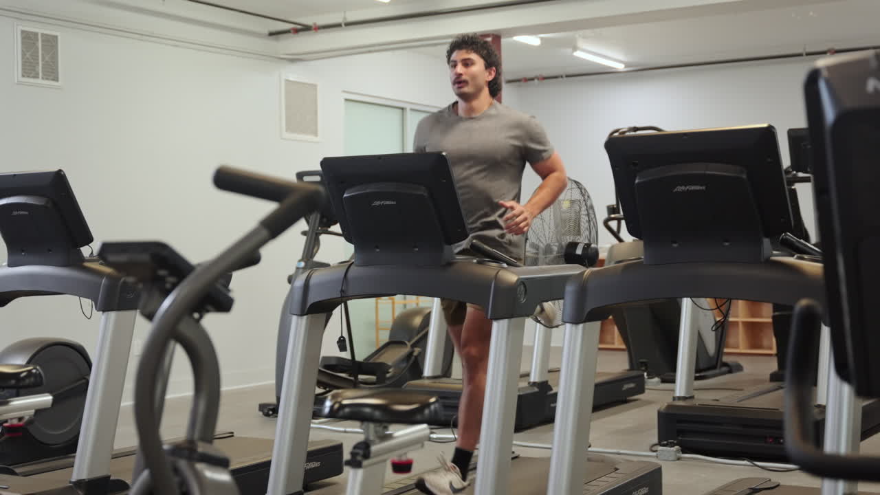 Man running on treadmill in gym, focused on fitness and determination