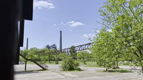 large old brick chimney of a historic factory site protrudes between nature, pipes grown in by books in the landscape park duisbrug north