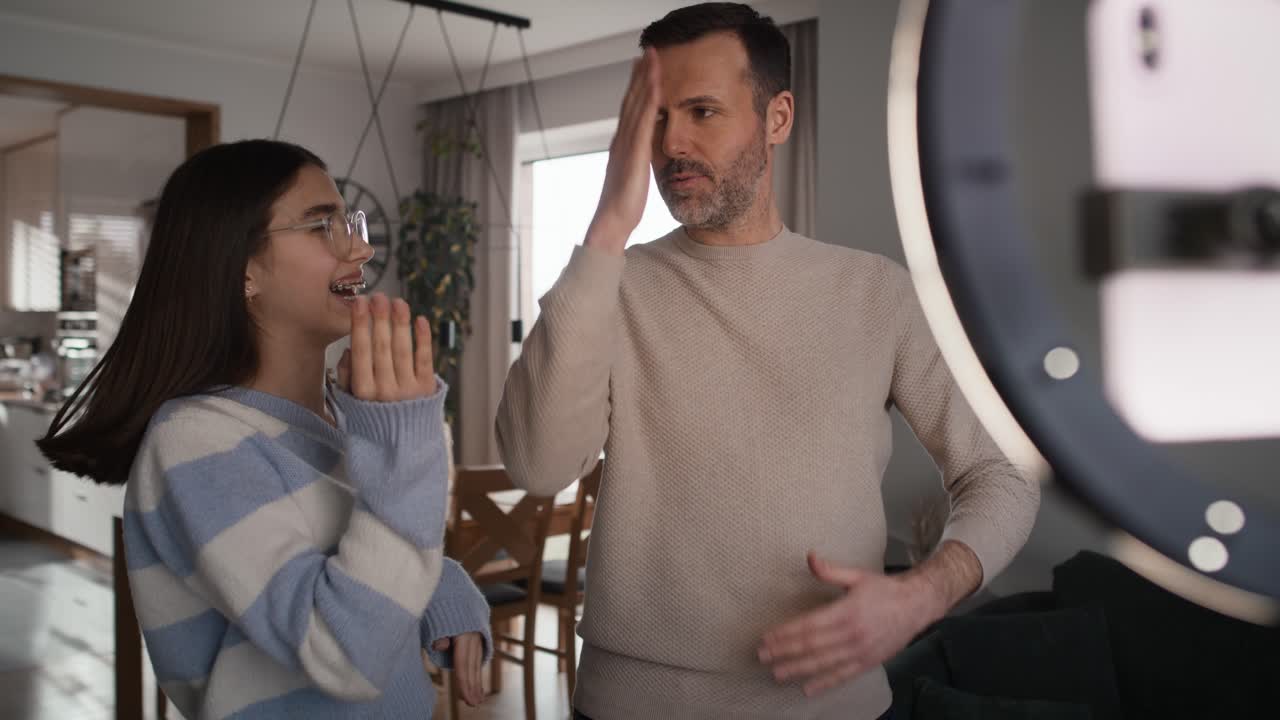 niña adolescente y su padre grabando baile para las redes sociales usando teléfono móvil