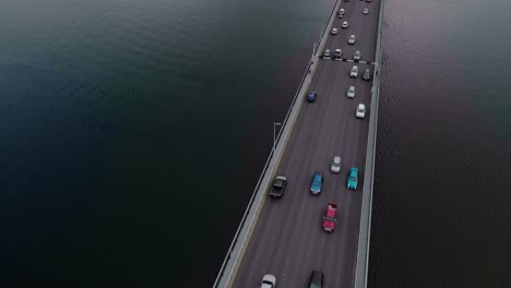 Aerial-top-view-of-vehicles-running-on-a-bridge-over-a-calm-river-in-Tasmania,-Australia