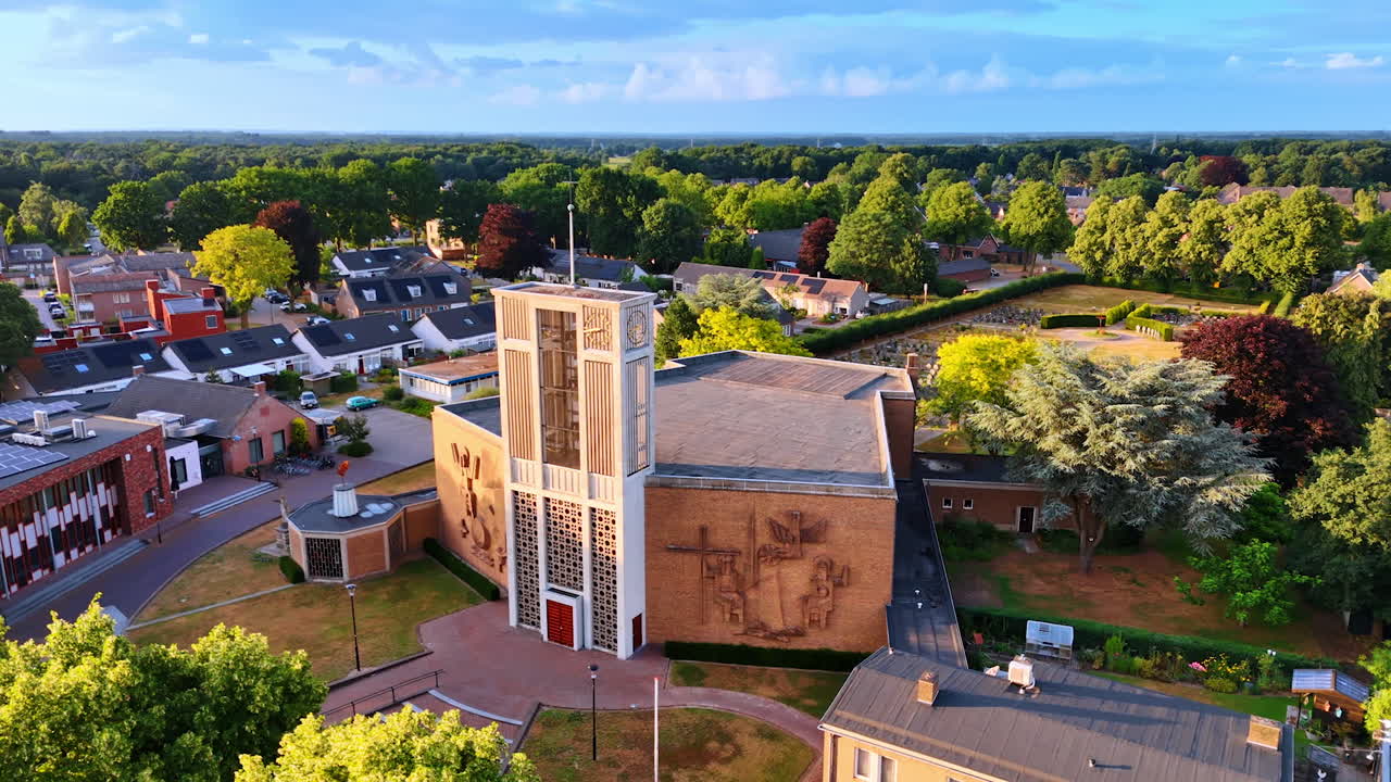 Unusual building of a church with bells tower over the entrance. Picturesque green panorama of Overloon, Netherlands. Aerial view