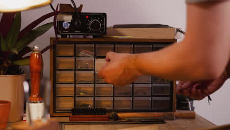 Worker-seeks-right-metal-rivets-in-organizer-in-workshop