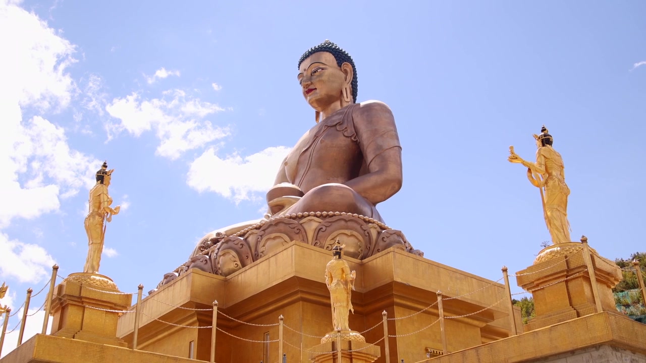 La telecamera si sposta a sinistra attraverso la statua del Buddha Dordenma e i guardiani Bodhisattva dorati in Bhutan
