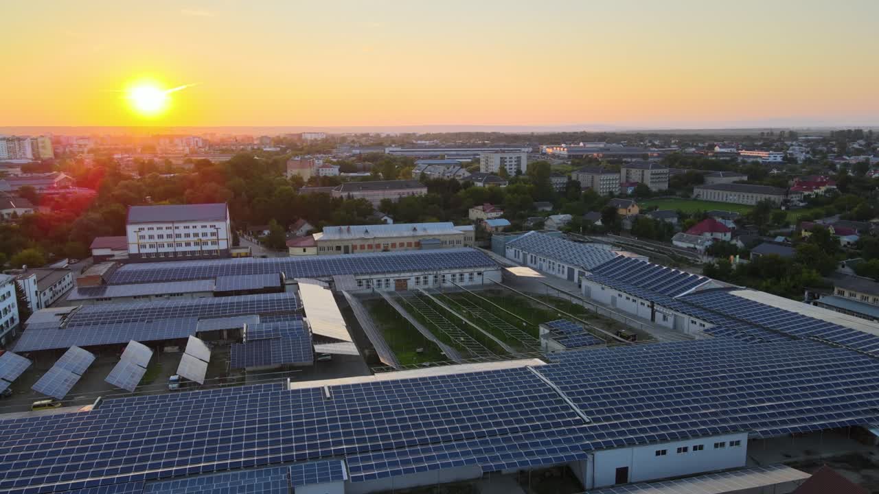 воздушный вид голубых фотоэлектрических солнечных панелей, установленных на крыше промышленного здания для производства зеленого экологического электричества при заходе солнца. производство концепции устойчивой энергии