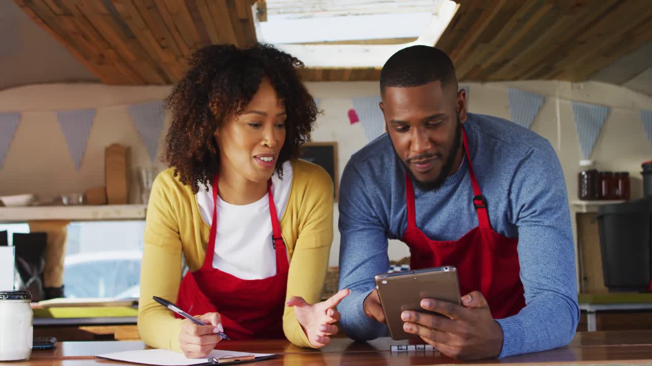 African american couple smiling while using digital tablet in food truck