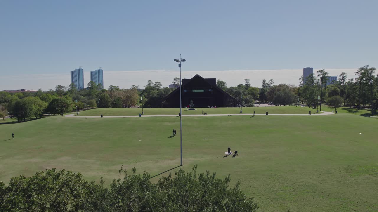 Aerial - Reveal of Hermann Park over a tree on a sunny day in Houston, TX