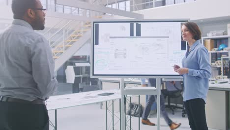 en el equipo de ingenieros y técnicos de la instalación de diseño industrial tienen una reunión, la especialista femenina conduce la sesión informativa, habla y dibuja en la pizarra digital interactiva con conceptos de prototipos de automóviles