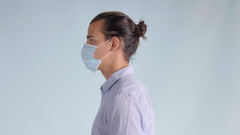 demonstration of young man putting on protective face mask, closeup profile