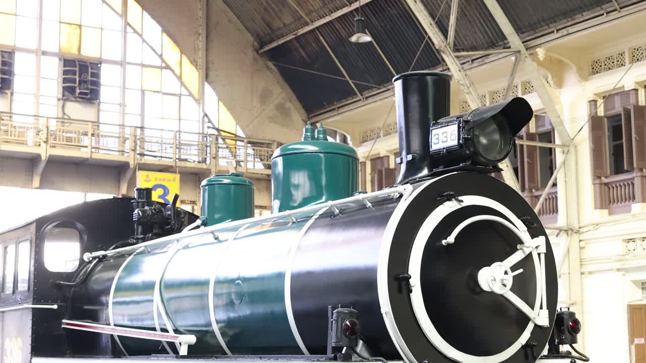 Slow lateral pan of restored steam locomotive display in bright indoor railway museum lighting
