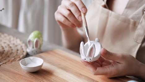 happy easter, handcraft woman painting easter bunny made from cold porcelain stand for easter eggs, creative workshop, hobby and preparation for easter holiday