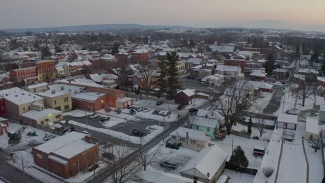 aerial establishing shot of small town in usa, covered in snow at sunset, sunrise