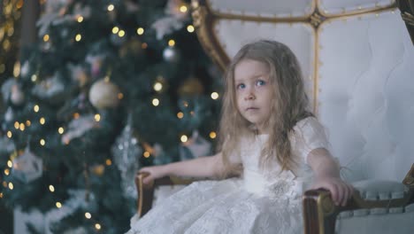 cute-girl-in-dress-with-laces-poses-in-armchair-at-Christmas