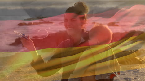 animación de la bandera de alemania sobre una madre caucásica feliz con un niño soplando burbujas en la playa