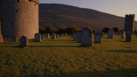 ancient gravestones and round tower in a serene cemetery at golden hour