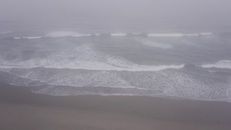 dramatic ocean waves crashing on a misty beach