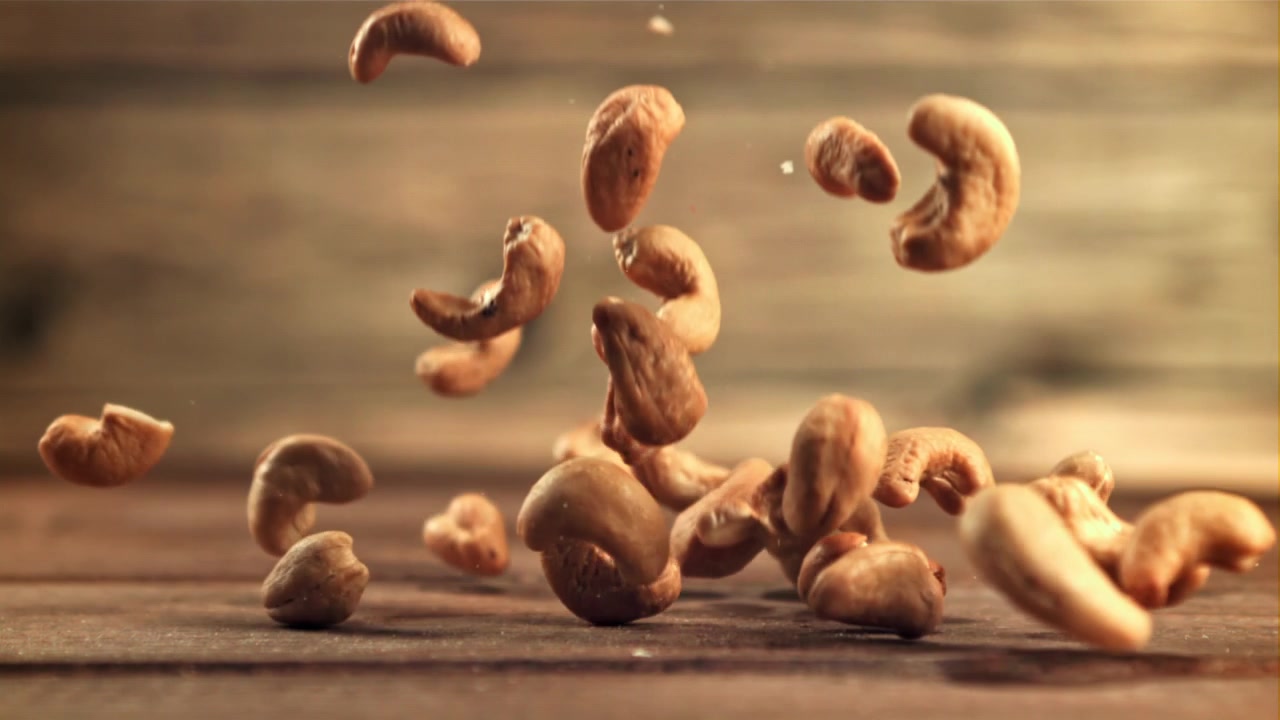 Cashew Nuts Falling onto a Wooden Surface in Slow Motion