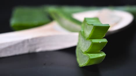 Fresh-Aloe-Vera-Sliced-on-the-black-background,-green-herb-concept-for-cosmetic-and-skincare-product-presentation,-round-smooth-motion