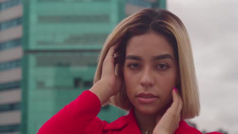 en port of spain, trinidad, una joven de ascendencia hispana, vestida con un vestido rojo, está de pie en un techo con edificios altos en el fondo de cerca