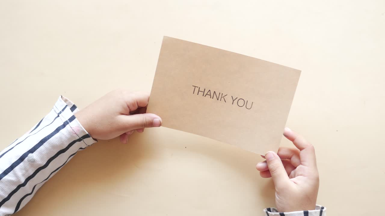 niño con una carta de agradecimiento en la mano,